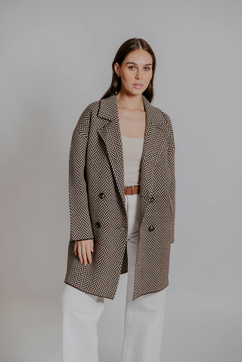 Woman wearing a patterned coat against a plain background