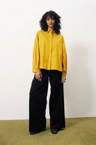 Person wearing a yellow shirt and black pants on a white background