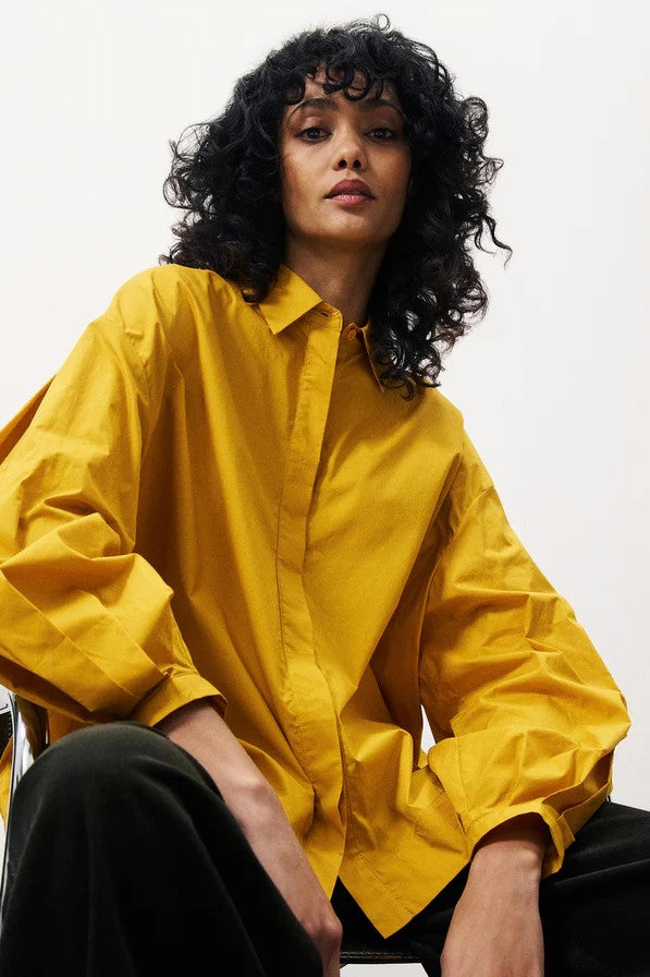 Person wearing a yellow shirt with black pants on a white background