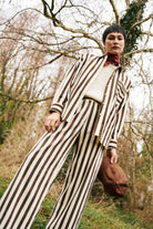Person wearing a striped brown and off white suit in a forest setting