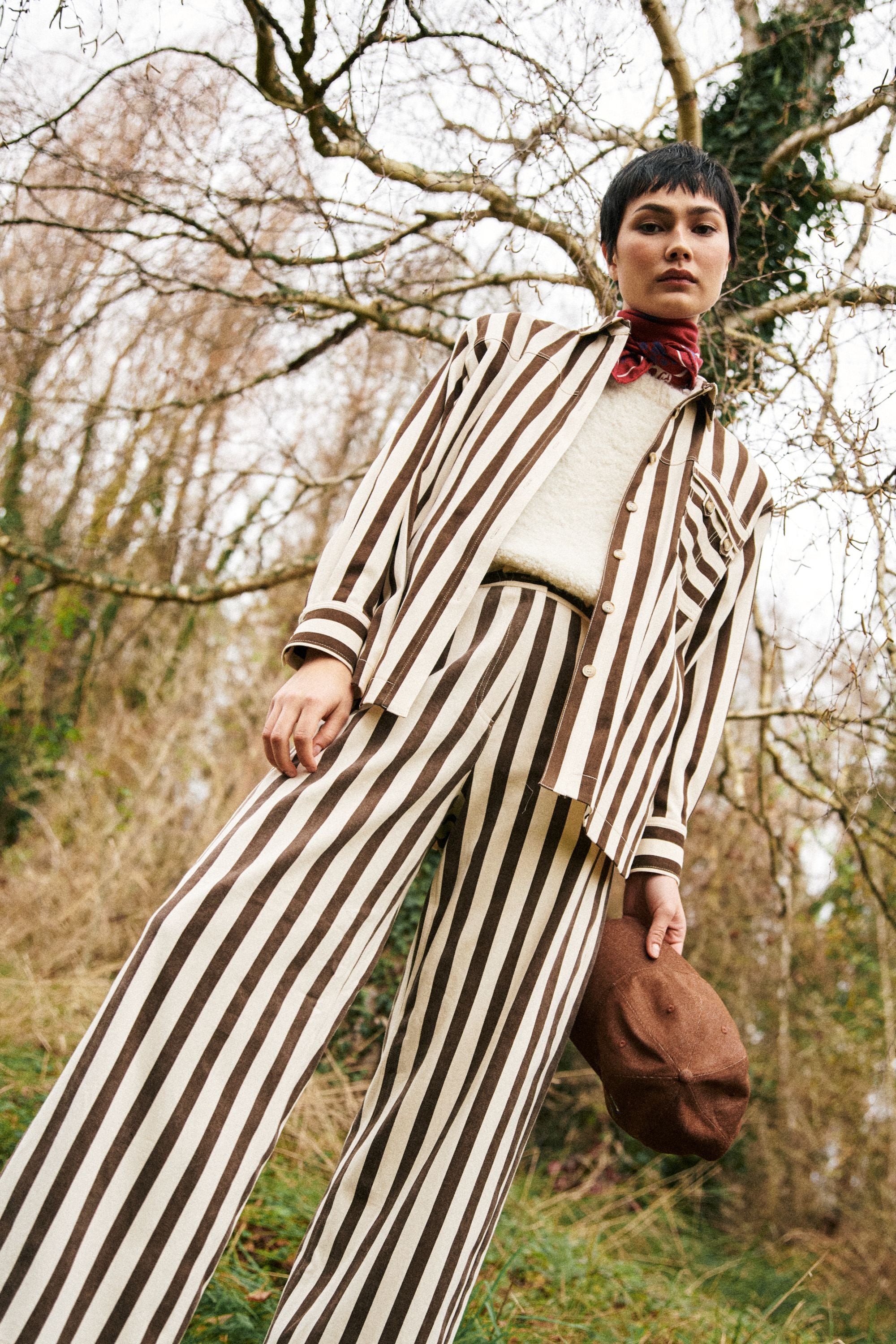 Person wearing a striped brown and off white suit in a forest setting