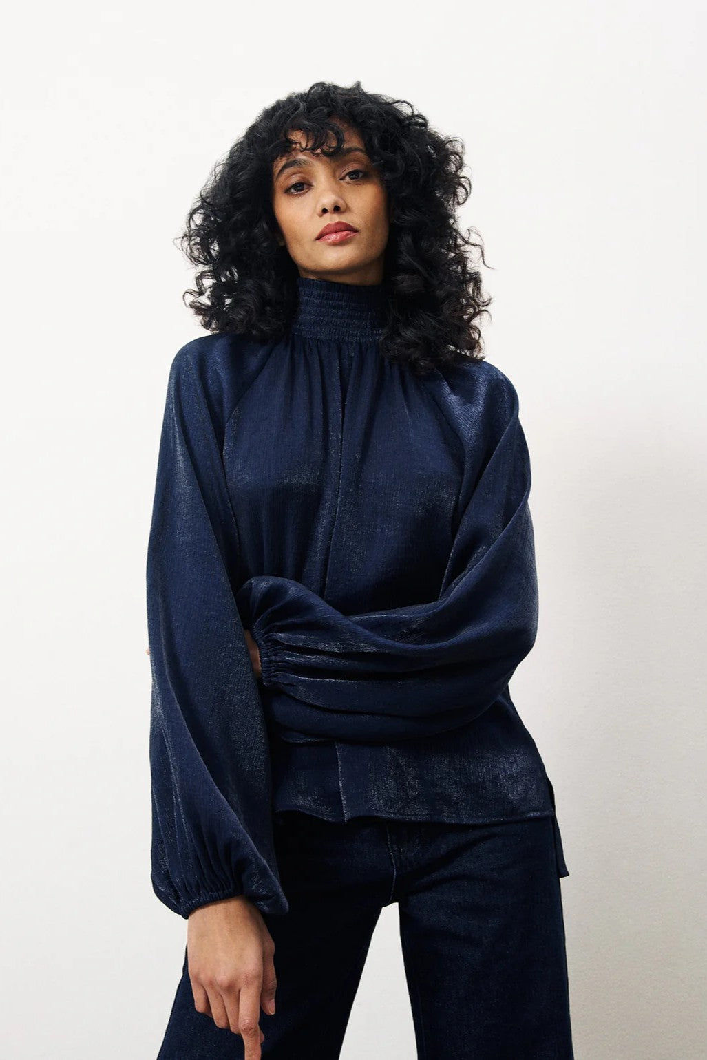 Woman wearing a navy blue top and pants against a white background