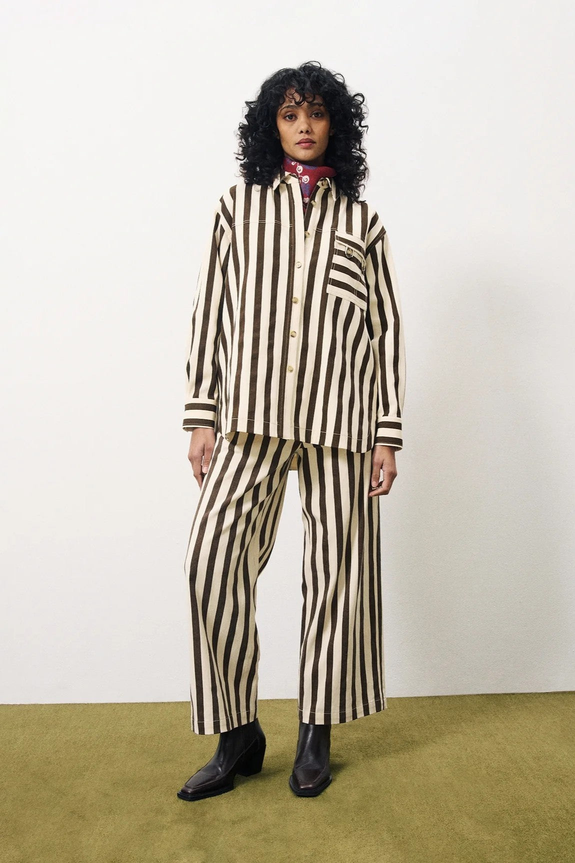 Person wearing a black and white striped suit with a red scarf against a white background