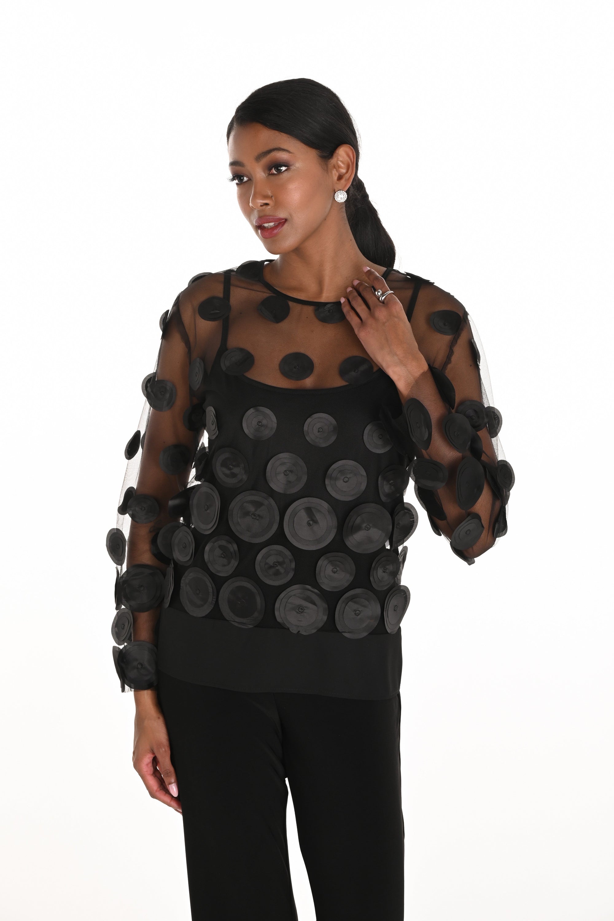 Model wearing a black sheer top with circular patterns on a white background