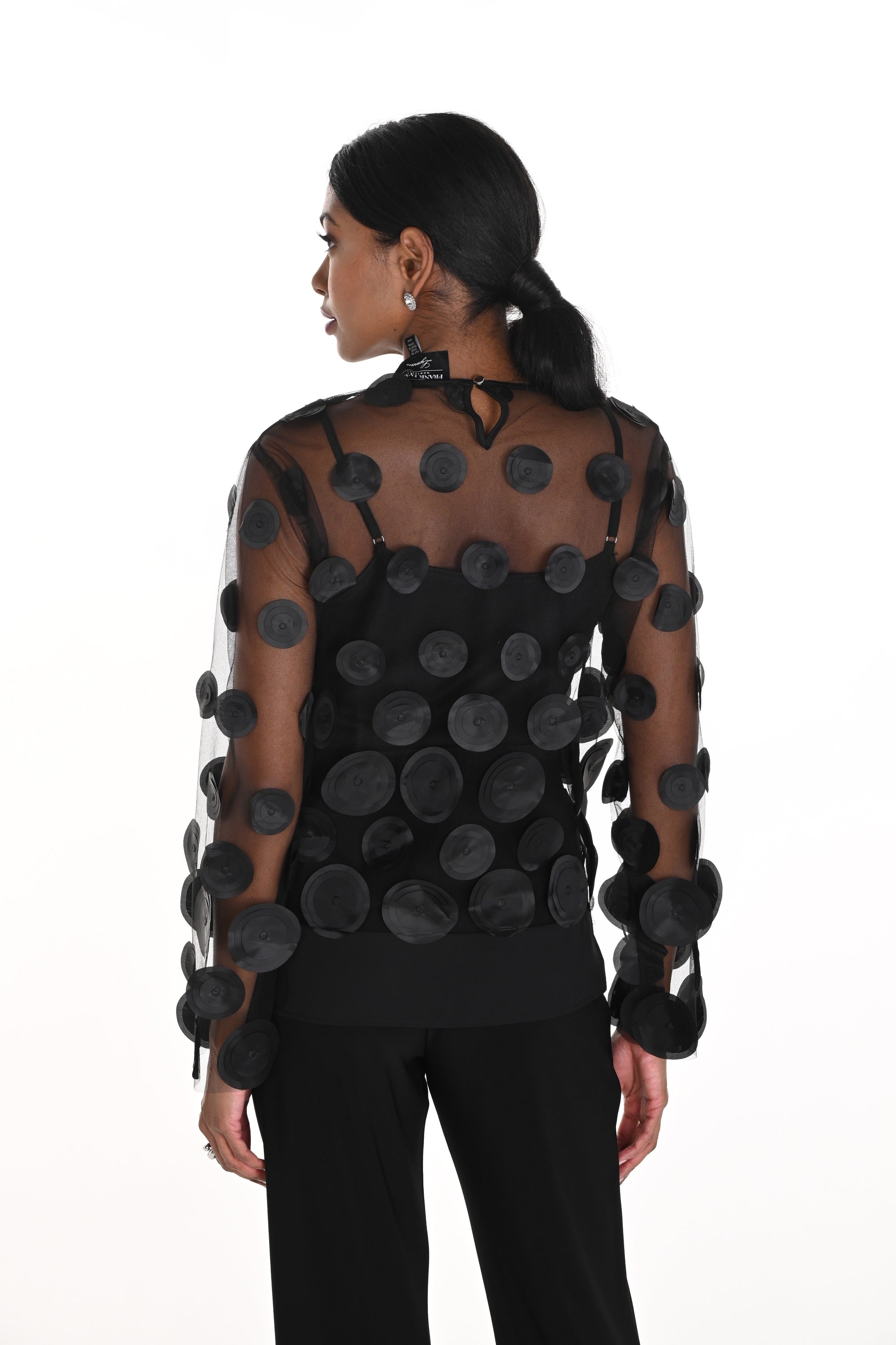 Woman wearing a black sheer top with circular cutouts on a white background