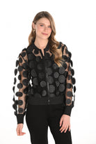 Woman wearing a black jacket with circle appliques on a white background