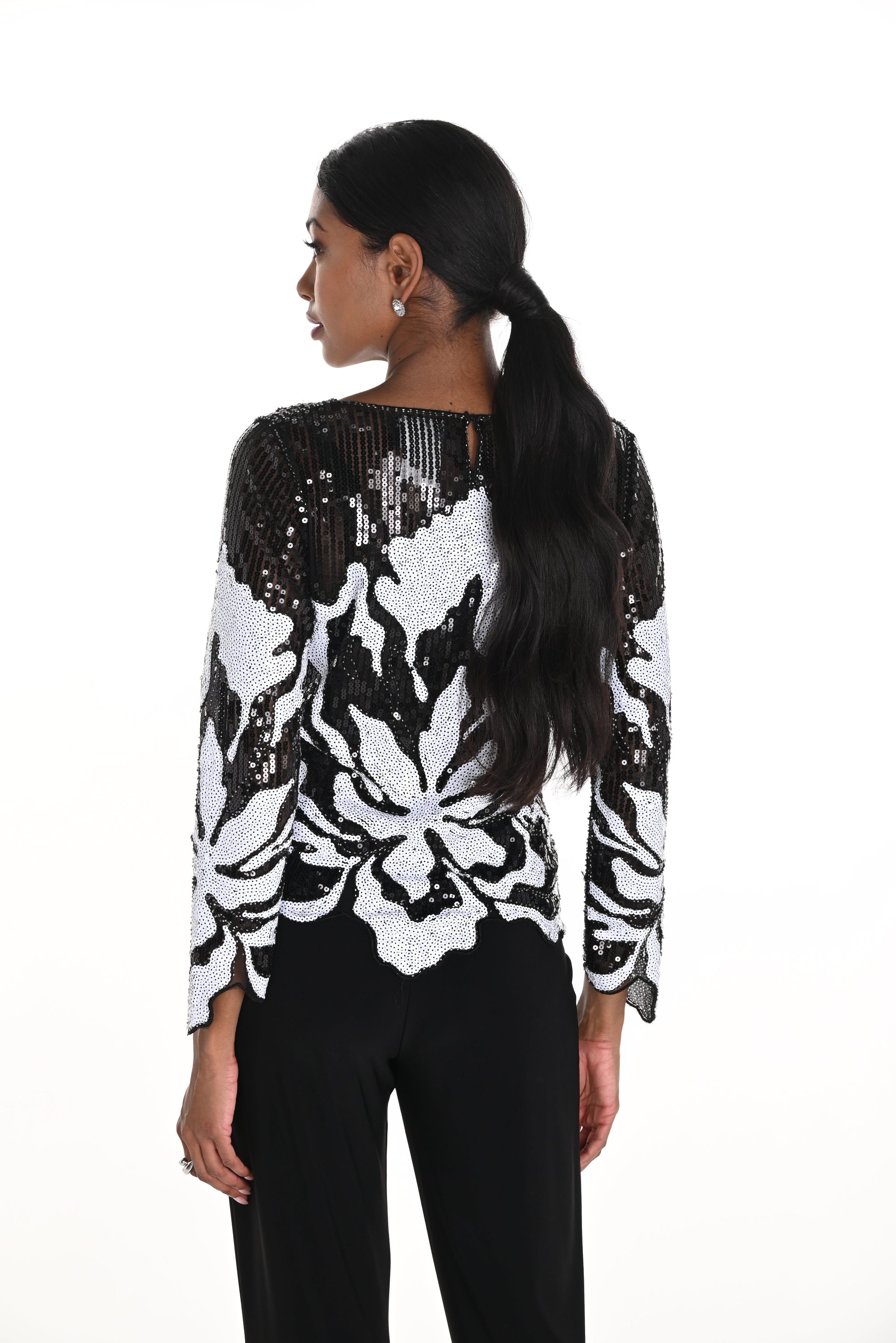 Woman wearing a black and white sequin floral top back