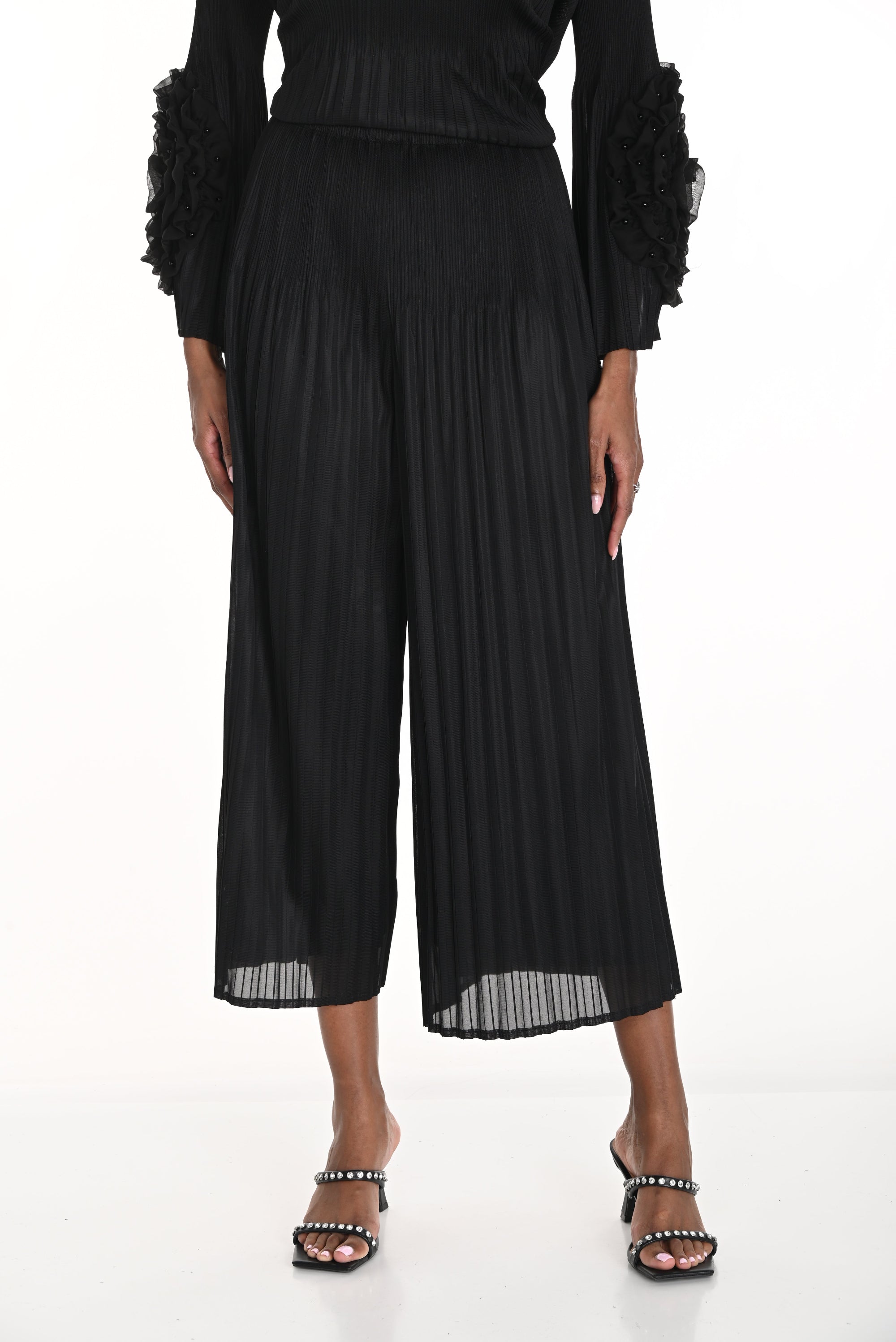 pleated black wide leg pants worn by model against white background