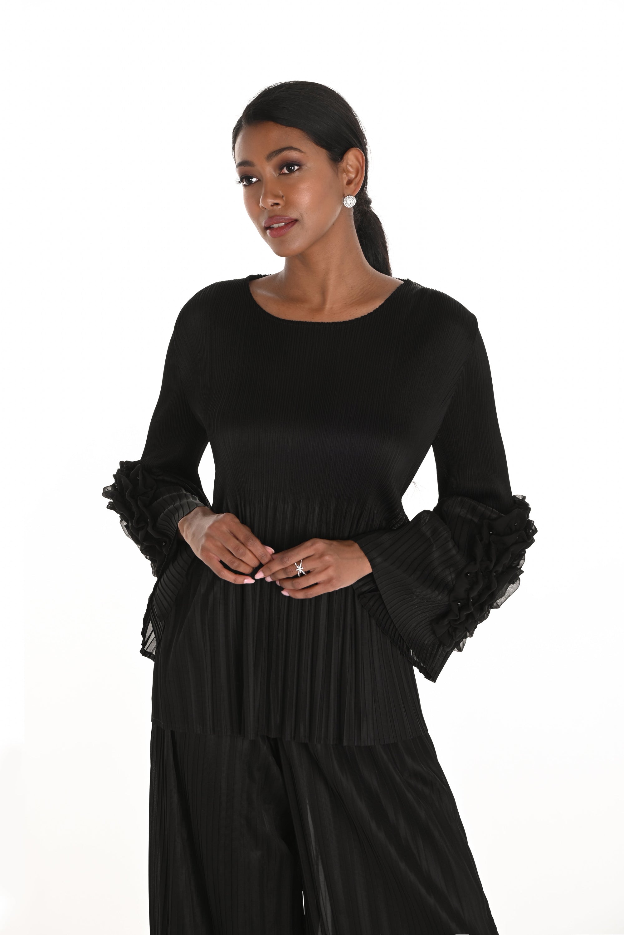 Woman wearing a black dress with ruffled sleeves on a white background
