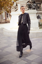 Woman in a black outfit standing in front of a statue in an urban setting