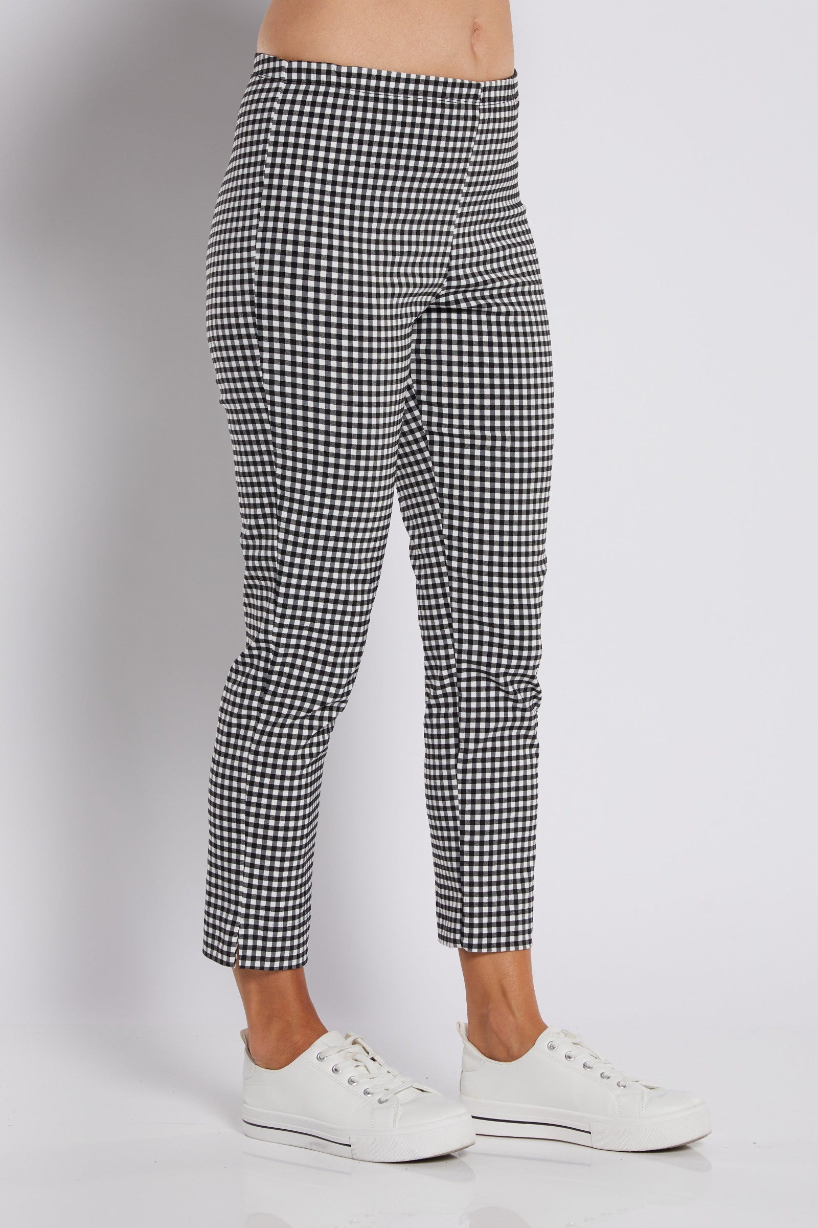 Black and white gingham patterned cropped pants worn by a model with white sneakers, shown from the waist down on a light gray studio background.