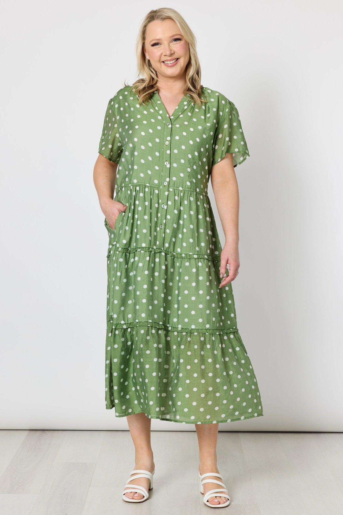 Woman wearing a green polka dot dress on a white background
