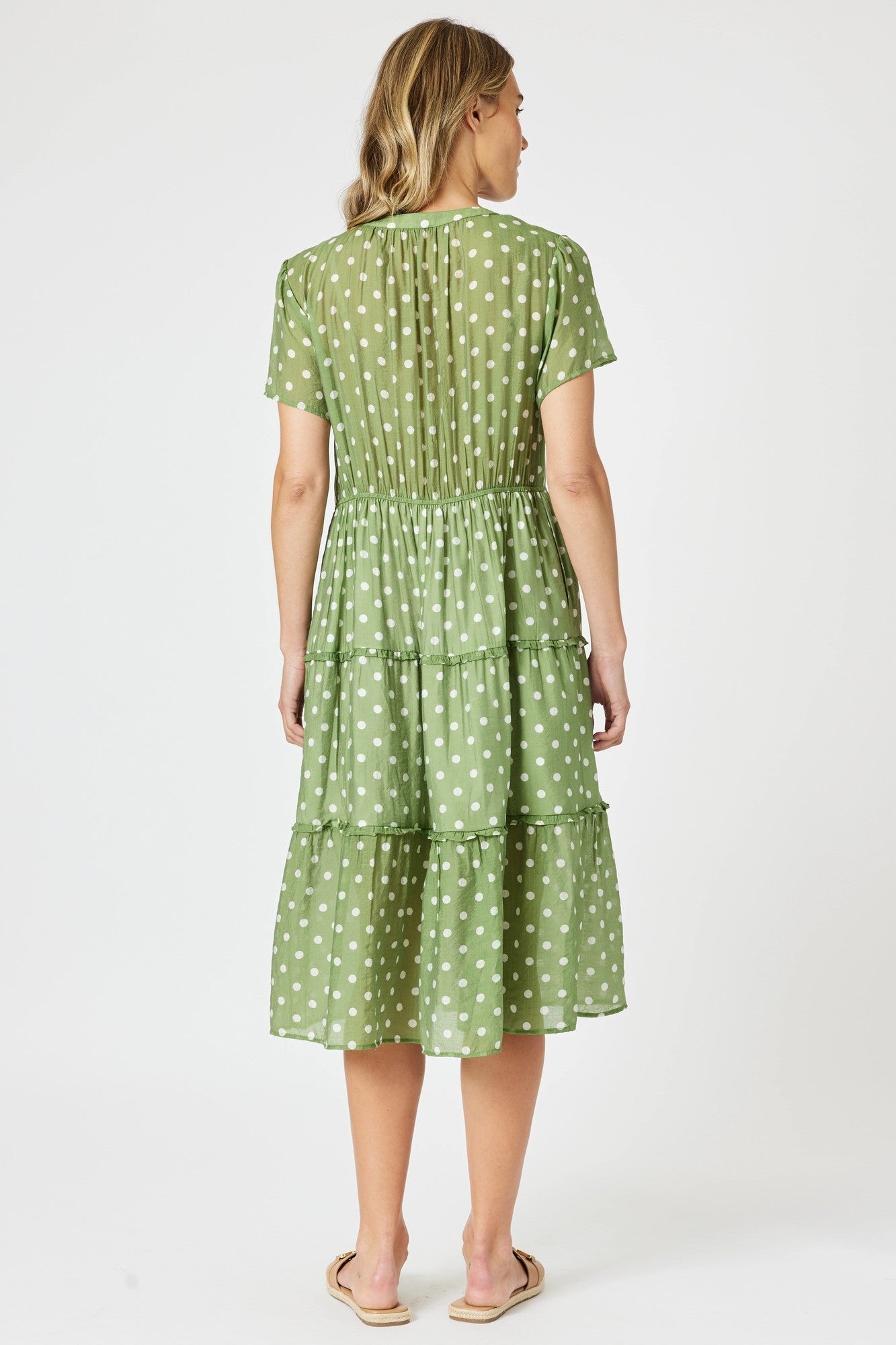 Woman wearing a green polka dot dress on a white background