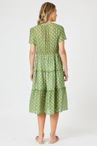 Woman wearing a green polka dot dress on a white background
