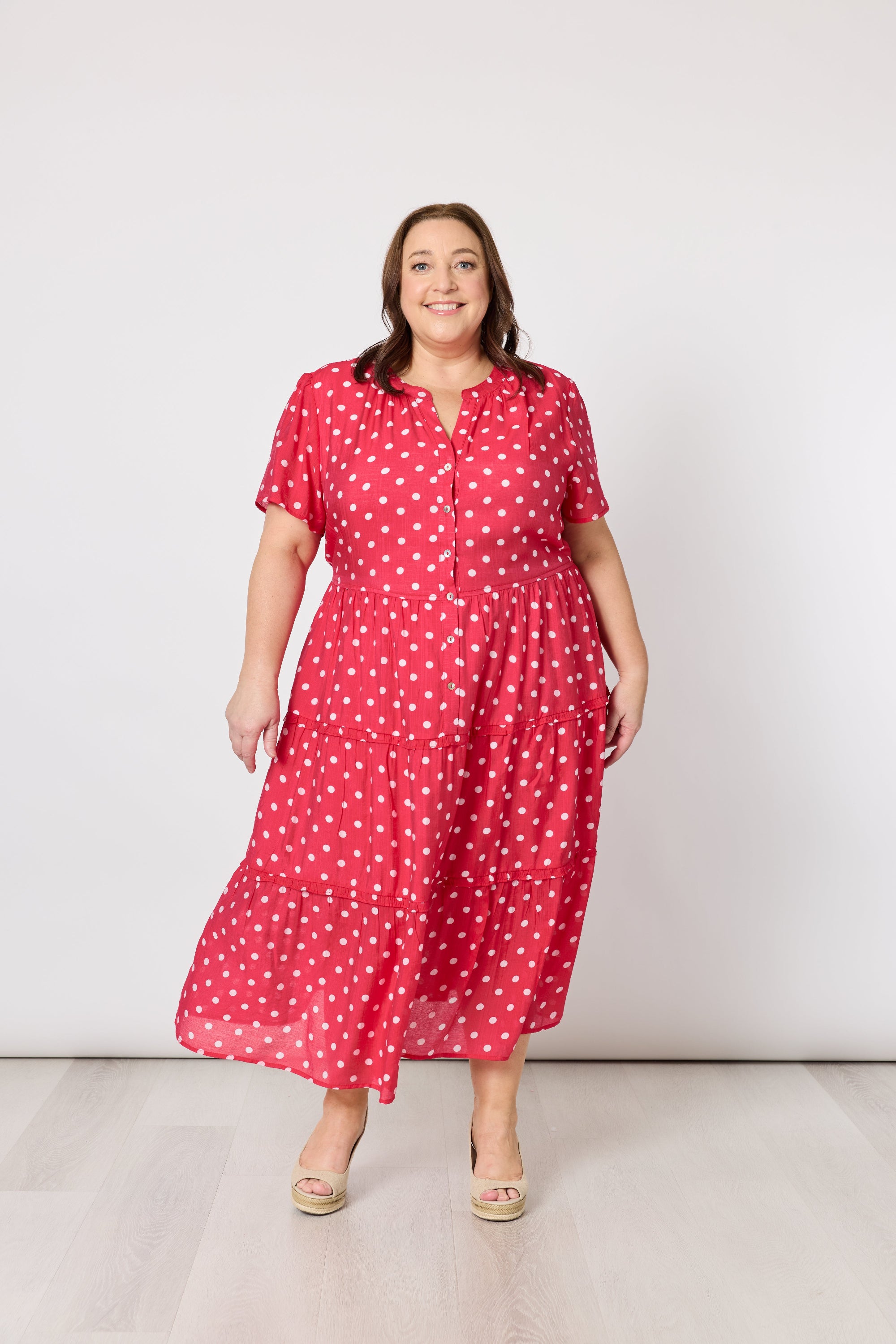 Woman wearing a red polka dot dress against a white background