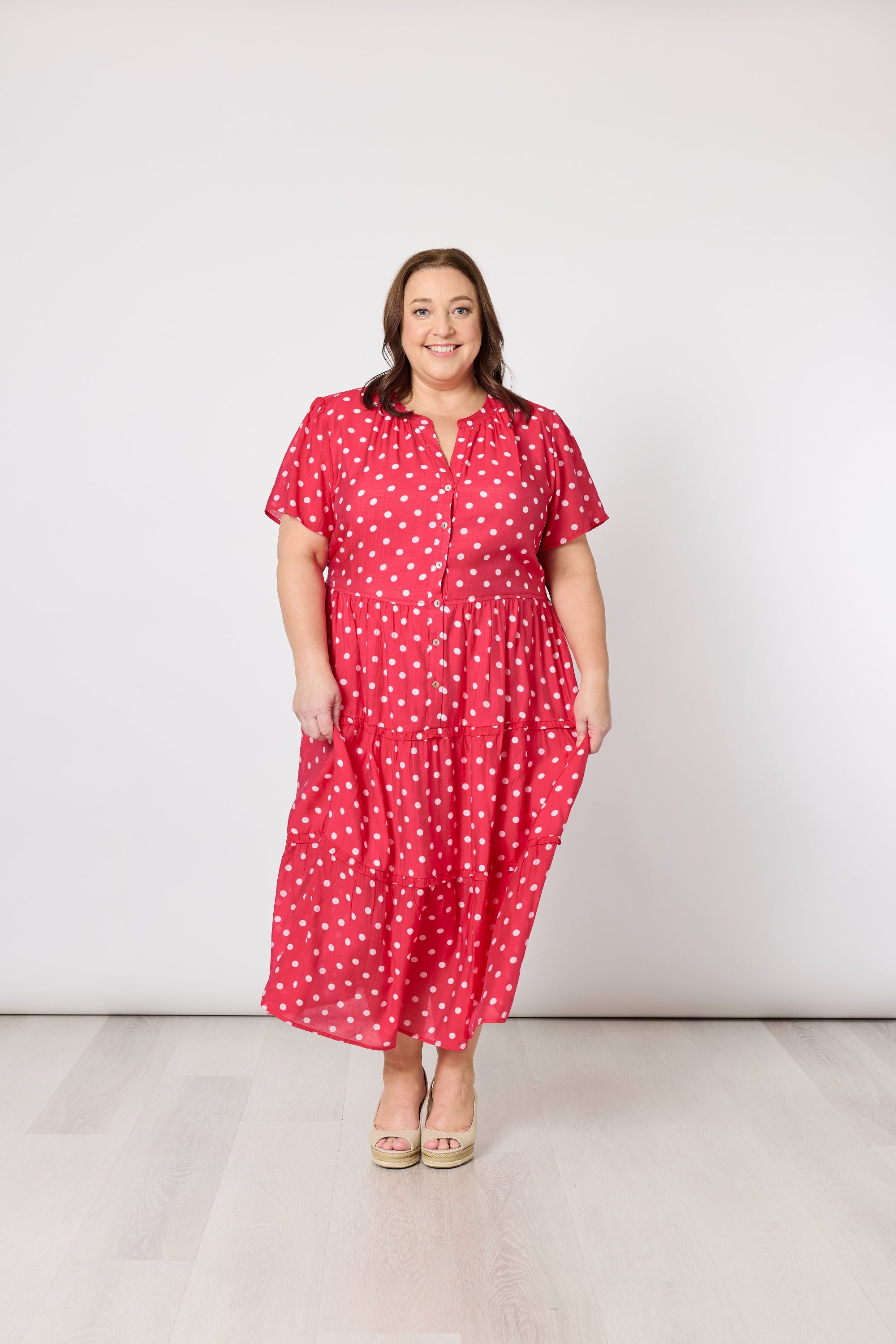 Woman wearing a red dress with white polka dots against a white background