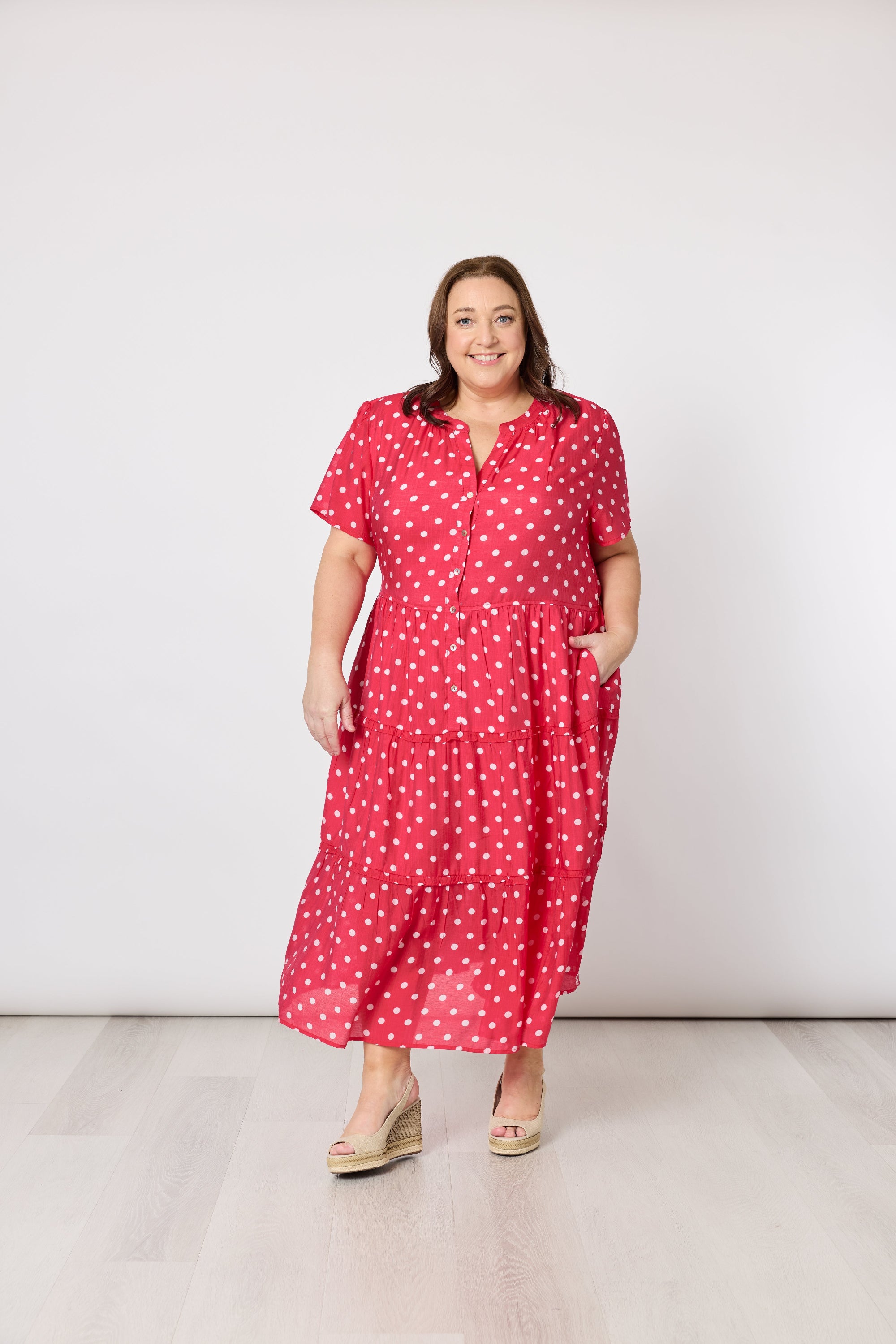 Woman wearing a red polka dot dress against a white background
