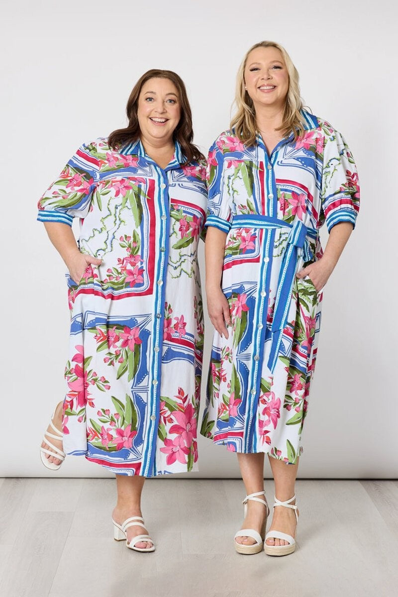 Two women wearing colorful floral dresses against a white background