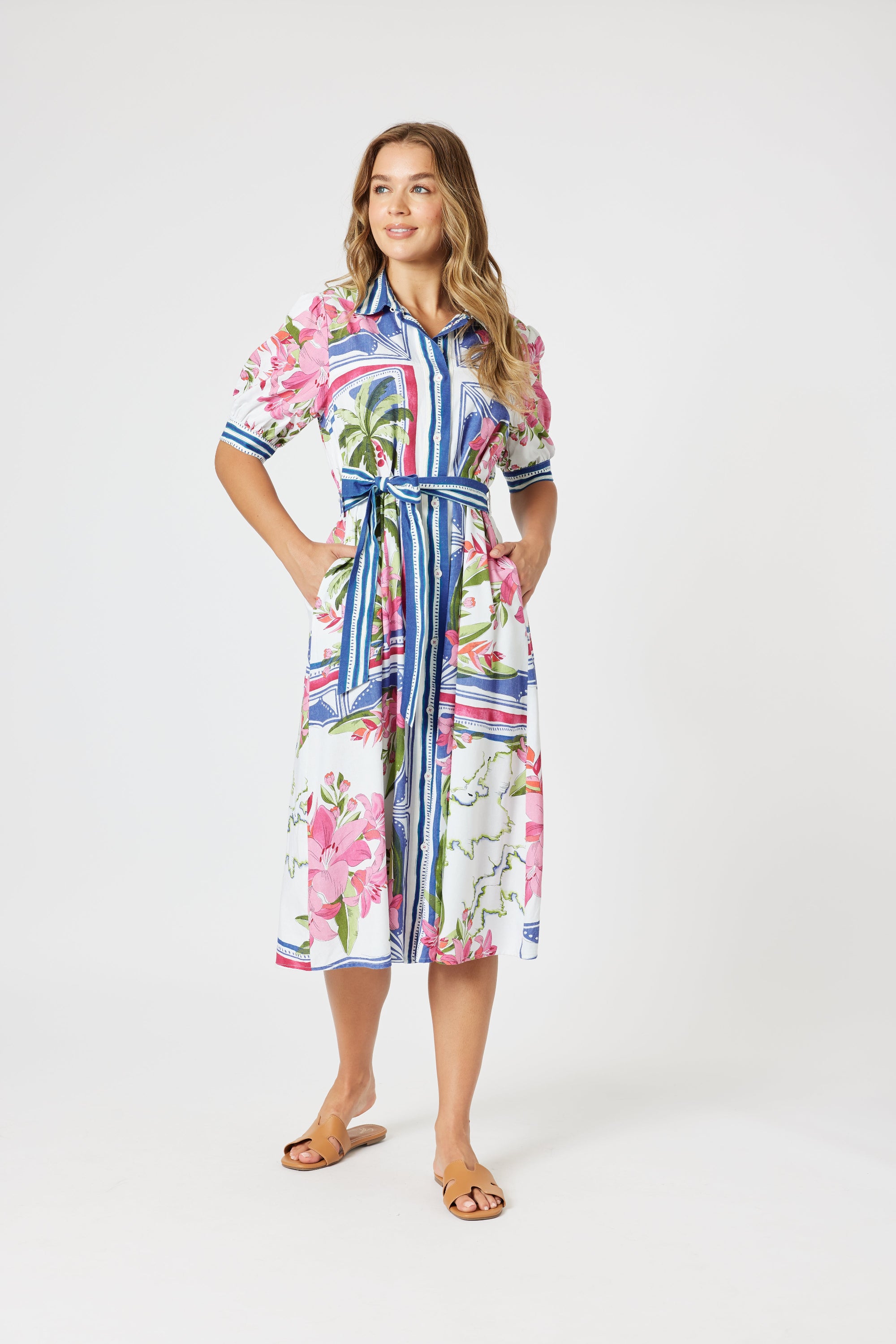 Woman wearing a colorful floral dress with a belt on a white background