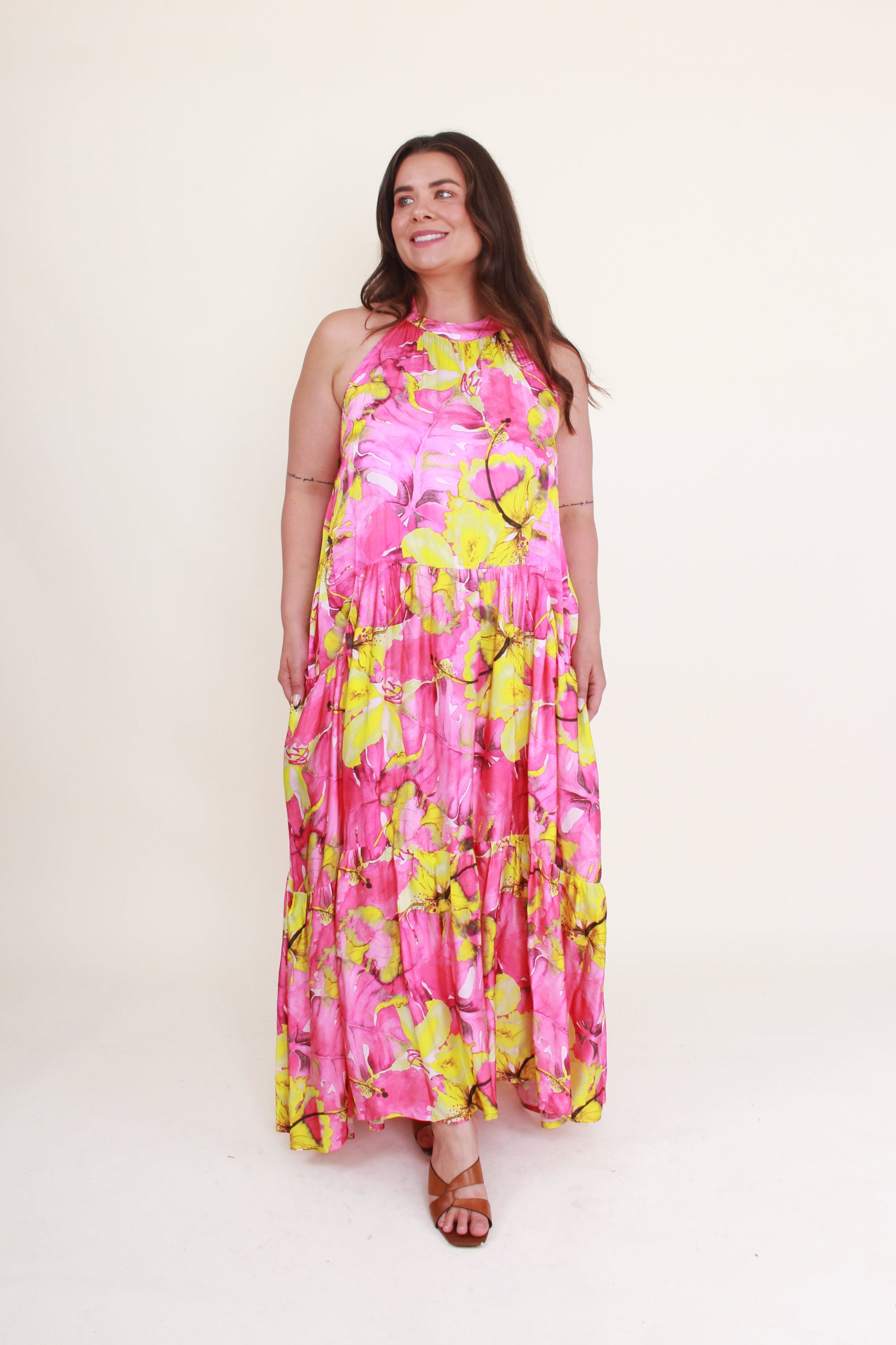 Woman wearing a pink and yellow floral dress on a white background