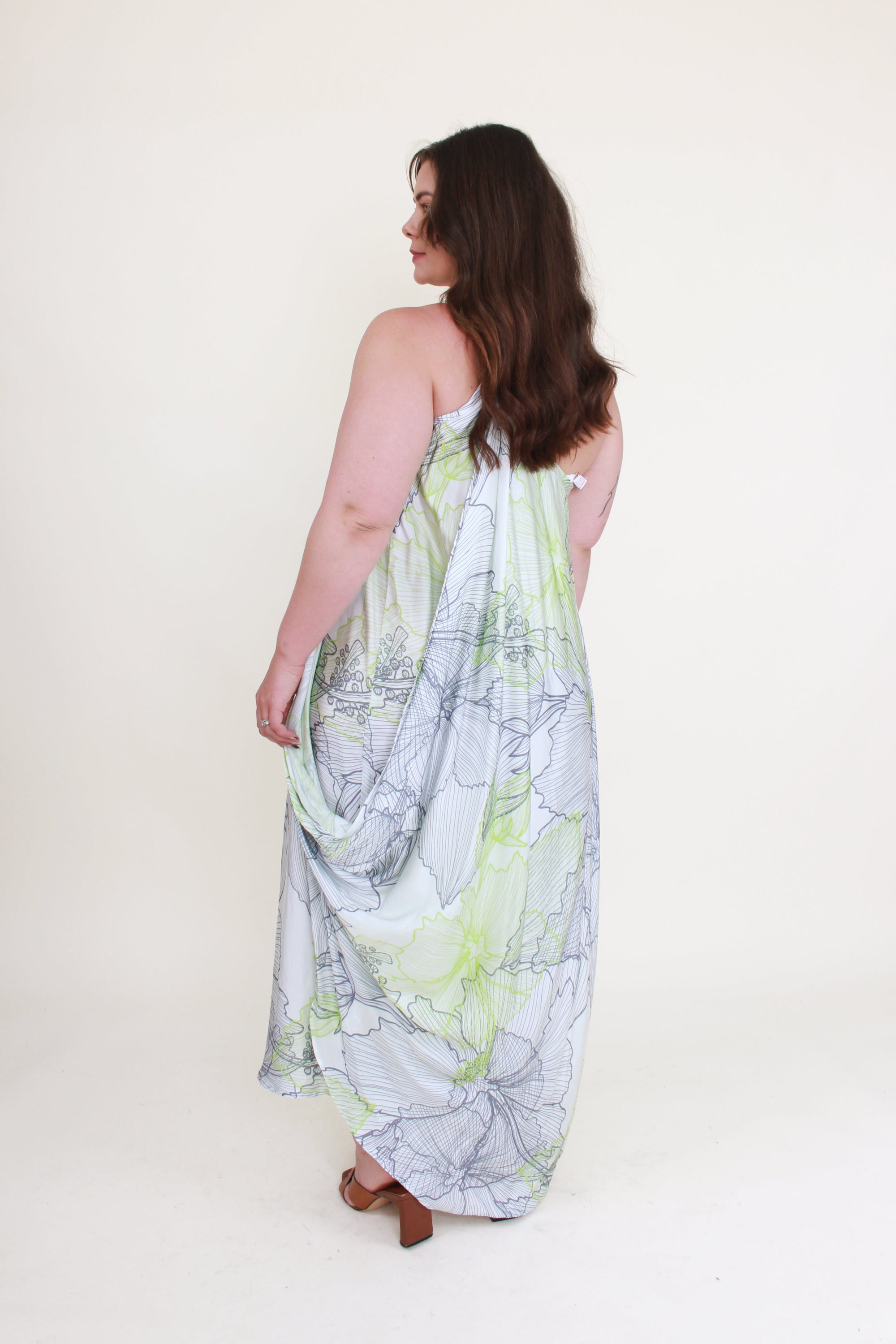 Woman wearing a long, light-colored dress with a subtle pattern on a white background