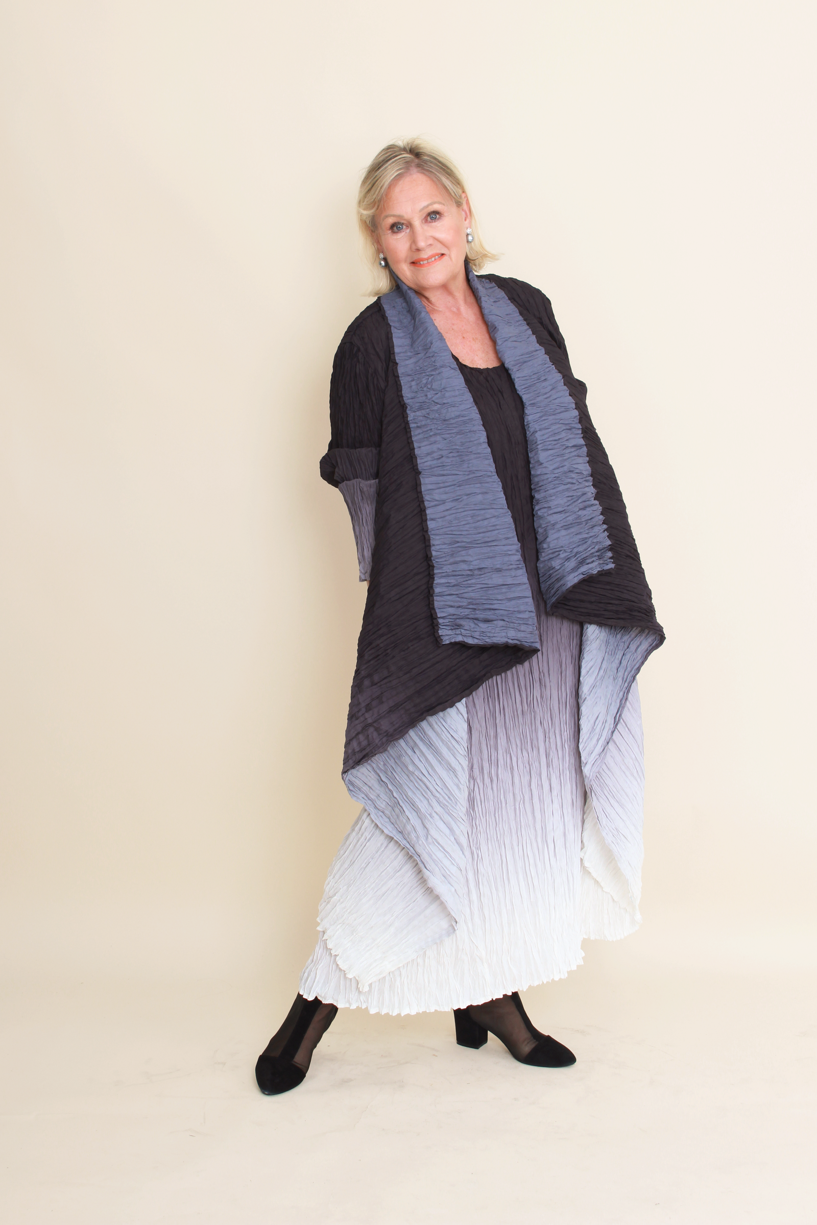 Woman wearing a black and gray patterned shawl over a white dress on a beige background