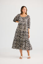 model wearing black cream long floral dress against white background