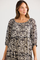 model wearing black cream long floral dress against white background