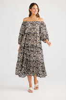 model wearing black cream long floral dress against white background