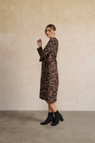 Woman wearing a patterned dress against a plain background