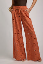 Orange lace pants worn by a person on a plain background
