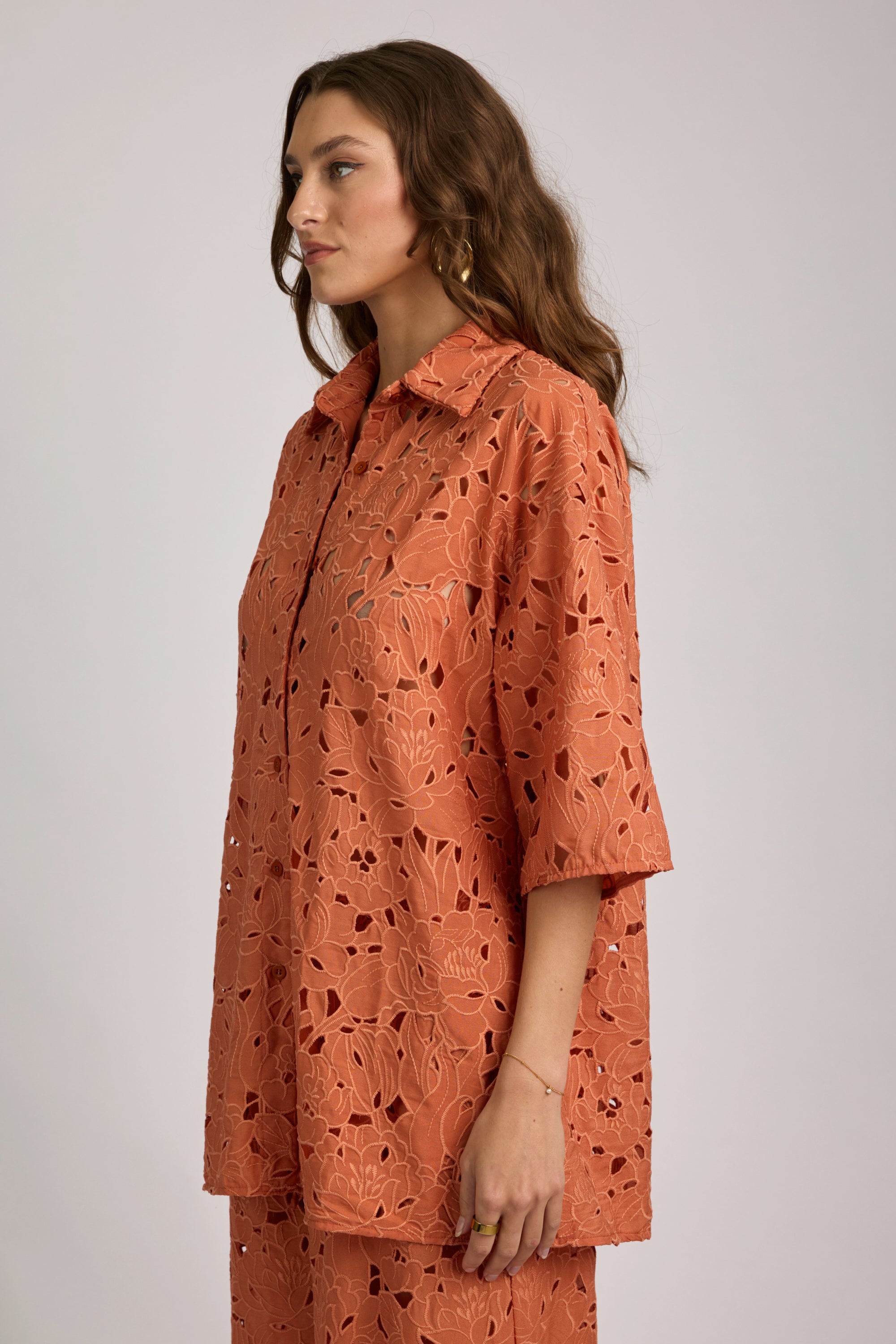 Woman wearing an orange patterned outfit on a plain background