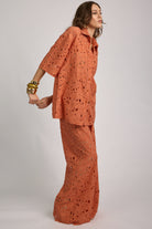 Woman wearing an orange patterned outfit on a plain background