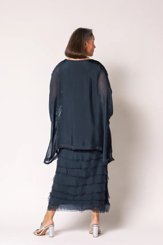 Woman wearing a navy blue layered outfit on a white background