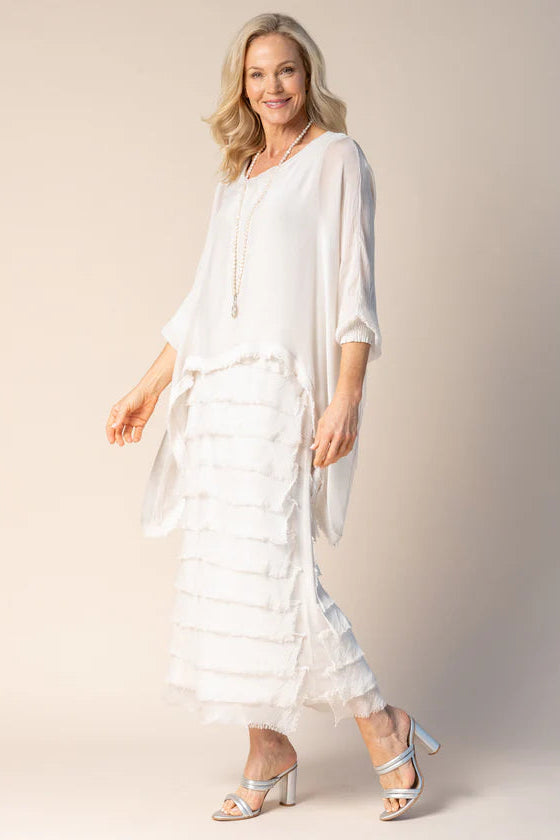 Woman wearing a white dress with a sheer overlay against a beige background