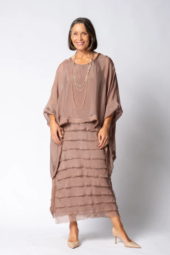 Woman wearing a brown dress with ruffled layers on a white background