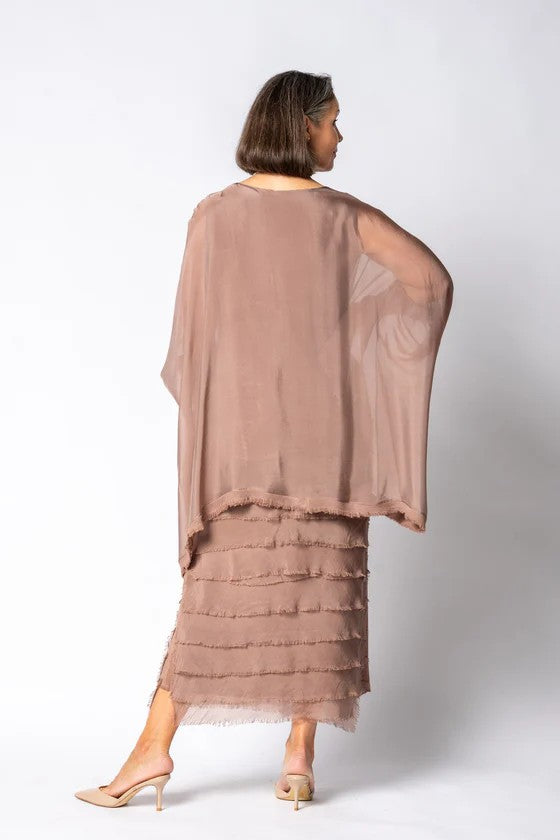 Woman wearing a brown dress with a sheer overlayer on a white background