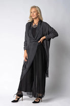 Woman wearing longline dark grey top over black dress on light grey background