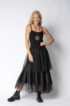 Woman wearing a black dress with a sheer overlay skirt on a white background