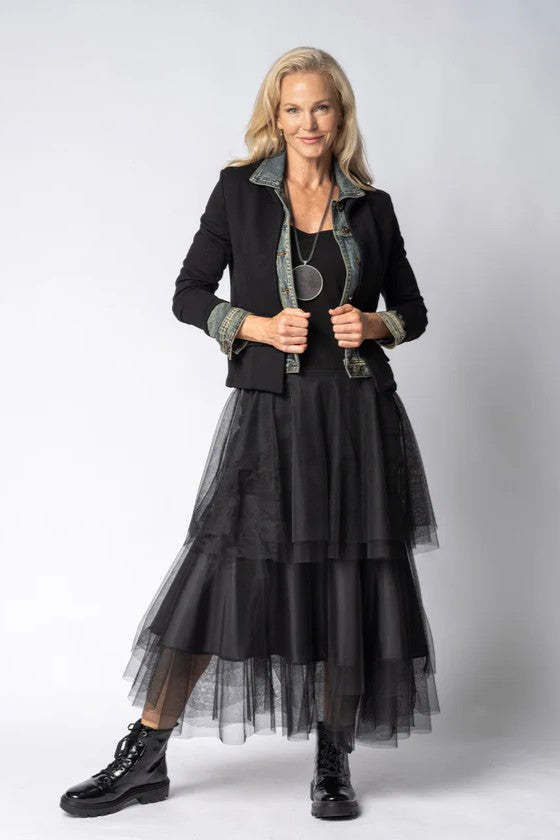 Woman wearing a black outfit with a sheer overlay skirt on a white background