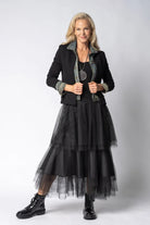 Woman wearing a black outfit with a sheer overlay skirt on a white background