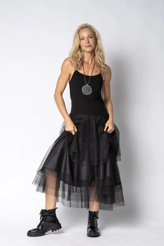 Woman wearing a black dress with sheer overlay skirt against a white background