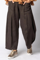 Brown wide-leg pants worn with a light brown top and sneakers on a white background