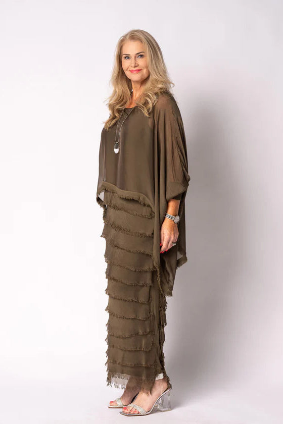Woman wearing a long, layered moss green dress against a white background