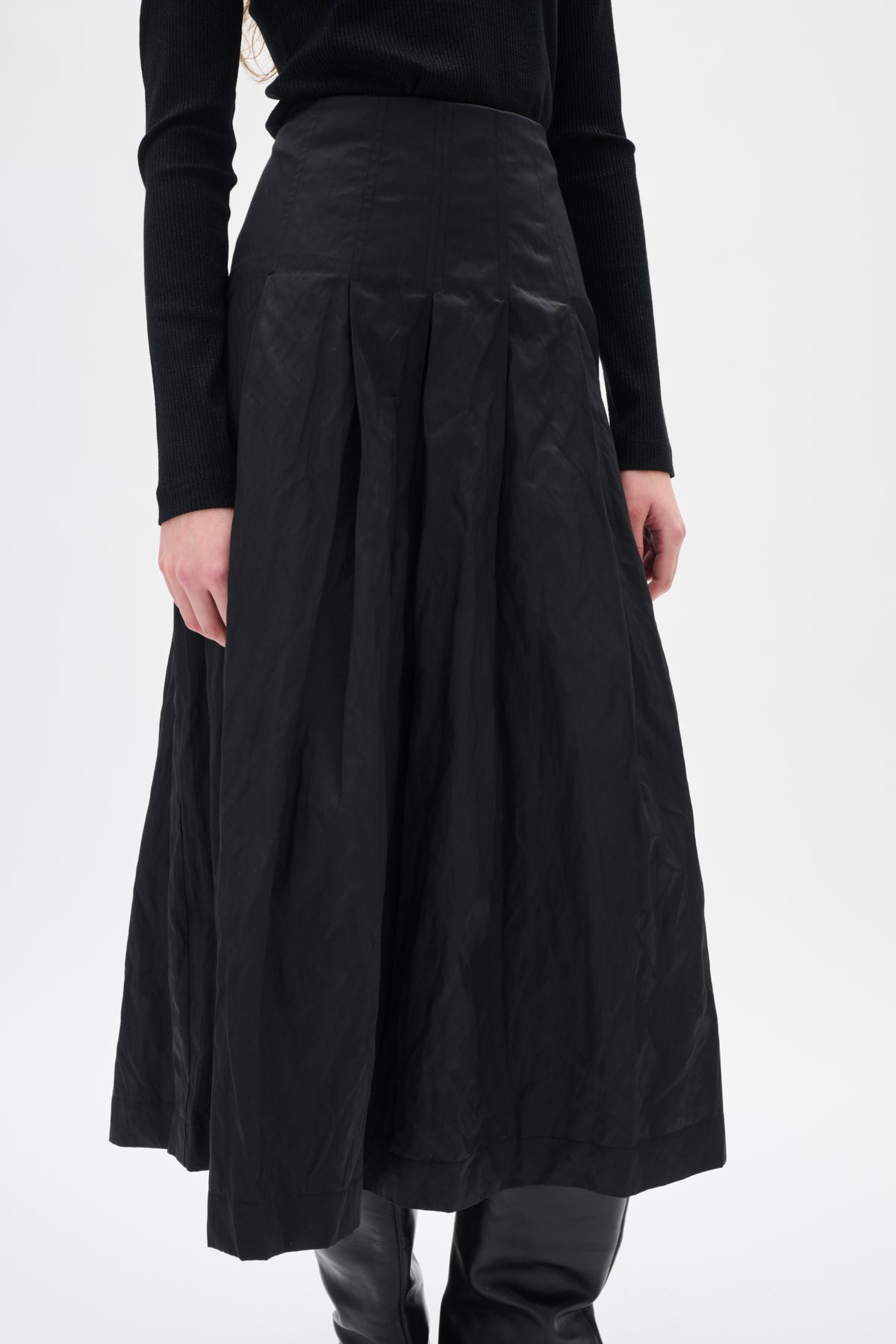 Woman wearing black pleated skirt on white background
