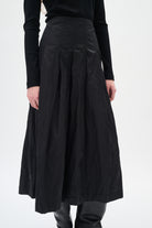 Woman wearing black pleated skirt on white background