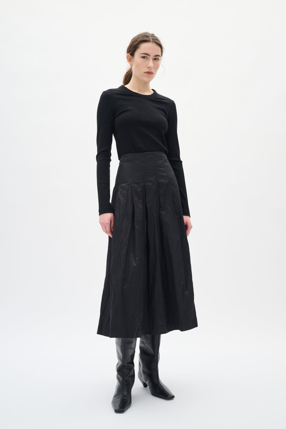 Woman wearing a black outfit with a skirt on a white background
