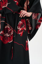 Black garment with red floral patterns on a white background close up