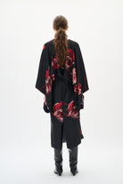 Person wearing a black dresswith red floral patterns from behind on a white background back angle