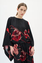 Woman wearing a black dress with red floral patterns on a white background